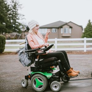 An independent young adult woman with cerebral palsy going about some of her daily routines.  She rides her wheelchair up a ramp in her specially equipped van, preparing to drive to her job.